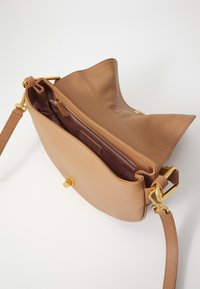 Borsa a mano in pelle color tan con esterno testurizzato. Presenta una chiusura in metallo dorato, una tasca interna con zip e una tracolla regolabile.