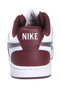 Baskets blanches avec un talon et des accents en cuir bordeaux. Dotées d'un logo à l'arrière, d'une tige texturée et d'une semelle en caoutchouc blanc.