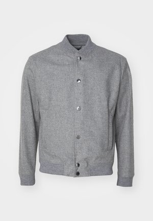 Sivá tkaná bunda s vysokým golierom, predným zapínaním na gombíky, bočnými vreckami a rebrovanými manžetami a lemom. Mäkko štruktúrovaný materiál, voľný strih.