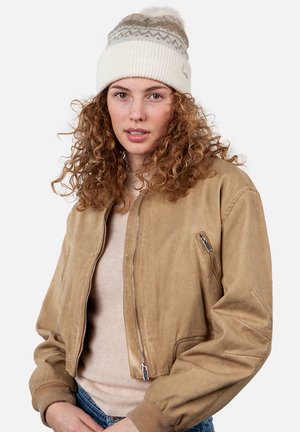 Bruine, cropped bomberjack gemaakt van zachte suede, met een ritssluiting aan de voorkant en zijzakken, gecombineerd met een crèmekleurige gebreide beanie met een pompon.
