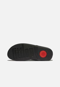 Suola di scarpa in gomma nera con superficie testurizzata, motivo scanalato e un accento circolare rosso con il marchio "fitflop".