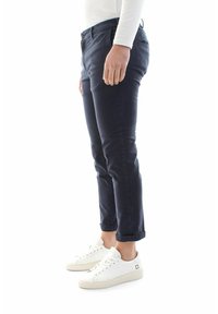 Pantaloni slim-fit blu navy con una texture liscia, caratterizzati da un orlo arrotolato e tasche frontali, abbinati a sneaker bianche.
