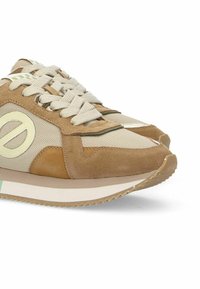 Scarpe sportive beige realizzate con materiali in suede e rete. Presentano lacci piatti, suole in gomma e un logo circolare sul lato. Accenti testurizzati visibili.