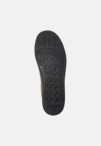 Suela de zapato de goma negra con patrones de agarre redondeados, una superficie lisa y logotipo grabado. Talla 42 indicada cerca del talón.
