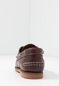 Braune Lederbootschuhe mit goldenen Ösen, weißer Naht und Gummisohle. Enthält das geprägte "Timberland"-Logo an der Ferse.