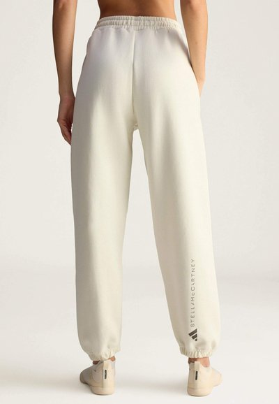 Licht crème tapered joggers met een elastische tailleband en boorden, met een subtiele logoafdruk aan de zijkant en een zachte textuur.