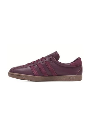 Sneaker in pelle bordeaux con lacci abbinati, tre strisce laterali, linguetta in suede sul tallone e suola in gomma marrone testurizzata, orientata verso destra.