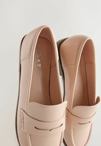 Lichtroze leren loafers met een soepele textuur, voorzien van een gestikte accent op de bovenkant en een ronde neusontwerp.