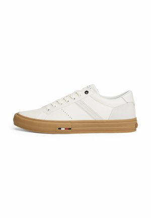 Hvide sneakers med en glat læderoverdel, tan gummisål, subtile perforeringer og en mærkeaccent i rød, hvid og blå.