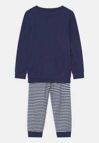 Marineblaues Langarmoberteil mit Rundhalsausschnitt; kombiniert mit gestreiften Hosen in Marineblau und Weiß. Weicher Stoff mit gerippten Bündchen an Ärmeln und Knöcheln.
