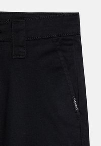Black denim pants featuring a smooth texture, standard waistband, side pocket, and a small branded label on the front.
