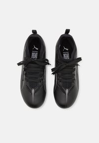 Zapatillas deportivas negras con una superficie texturizada, acentos en blanco contrastantes, cordones tradicionales y un diseño de perfil bajo.