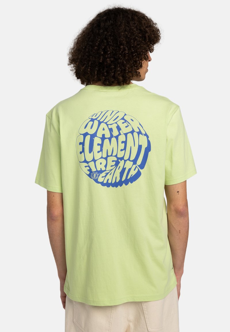 Lys grøn bomulds t-shirt med et stort blåt grafisk design, hvor ordene "VIND", "VAND", "ELEMENT", "ILD" og "JORD" fremstår i et cirkulært mønster.