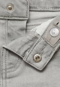 Harmaa denimpaita, jossa on nappi- ja neppariyksityiskohta. Tekstuuri on sileä, ja siinä on kontrastiväriset ompeleet sekä metallinen varuste.