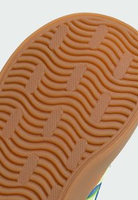 Gumeni potplat tenisice s uzorkom valova u narančastoj boji. Sadrži teksturirane elemente za dobro prianjanje i zaobljene rubove, dio je šarene atletske tenisice.