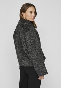 Pelēks vilnas un sintētisko šķiedru žakets ar teksturētu apdari, plašu apkakli un brīvu piegriezumu. Iespējas: garas rokas un īsa apakšmala.