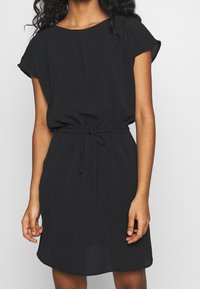 Robe noire à manches courtes avec une coupe décontractée et un cordon de serrage réglable à la taille. Tissu doux, encolure arrondie et ourlet légèrement évasé.