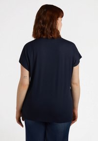 T-shirt blu navy con maniche corte arrotolate, realizzato in un tessuto morbido. Il retro è semplice, con una vestibilità rilassata e un orlo curvo.