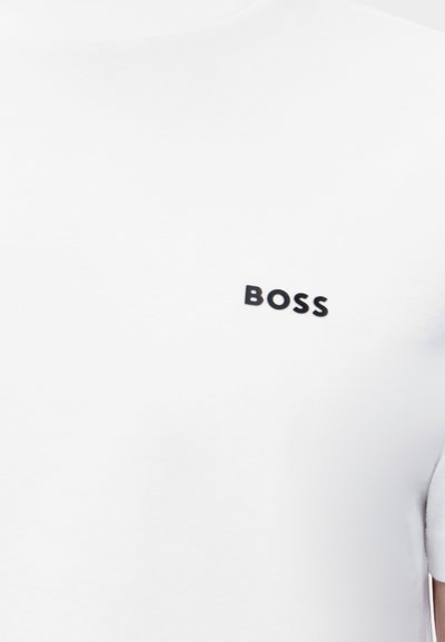T-shirt blanc à manches courtes, avec le mot BOSS en lettres majuscules noires sur la poitrine gauche.