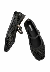 Zapatos planos negros con un patrón texturizado tejido, que cuentan con una correa con una hebilla metálica. Punta redondeada y interior acolchado.