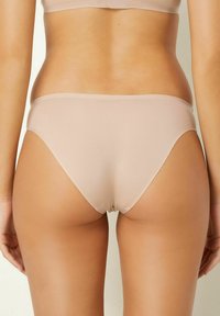 Beige bikini ondergoed met een gladde, rekbare textuur. Lage taille, minimale bedekking en naadloze randen voor een strakke afwerking.