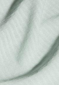 Ljusgrön tyg med en mjuk, strukturerad yta som har ett subtilt ribbat mönster, vilket visar en jämn och fin väv.