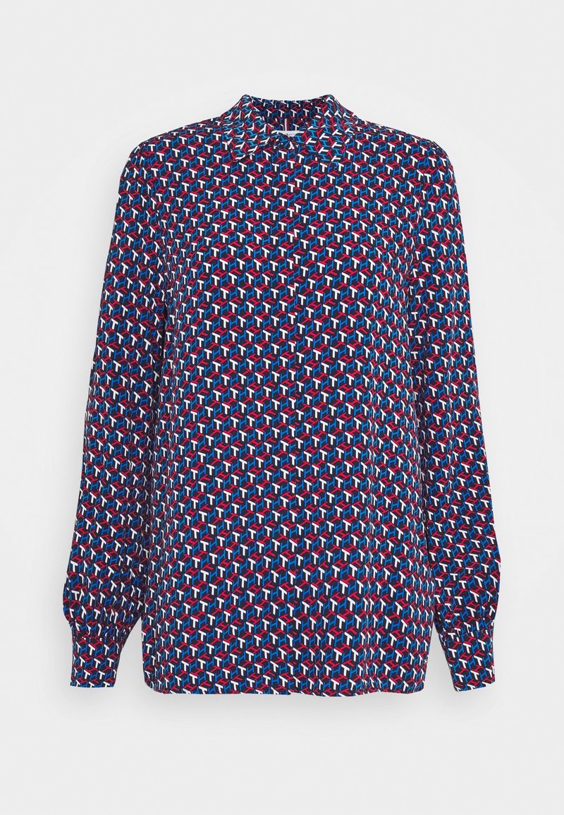 Blouse à manches longues avec motif géométrique rouge, bleu et blanc, col montant et poignets froncés.