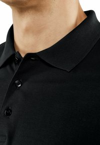 Czarna koszulka polo z teksturowanym materiałem, z płaskim kołnierzykiem i trzema guzikami przy szyi. Zbliżenie na kołnierzyk i guziki.