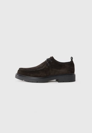 Dark brown suede lace-up shoe with black thick sole and pull tab on grey background, side view.
