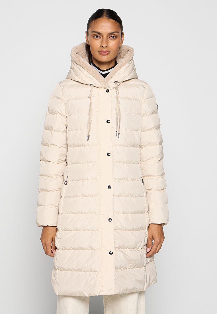 Jasno beżowy ocieplany płaszcz z kapturem, z podszyciem z sztucznego futra, sznurkami do regulacji oraz zatrzaskami, wykończony kieszeniami po bokach.