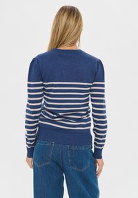 Námornícky modrý sveter s svetlobežovými pruhmi, so ribbovaným lemom a manžetami, navrhnutý s okrúhlym výstrihom a detailmi nafúknutých ramien.