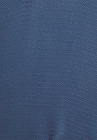Textilie s tmavě modrou látkou s jemným vzorem cik-cak a hladkou texturou, jednotnou barvou a vzhledem.