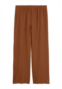 Pantalon large côtelé de couleur rouille avec taille élastique et détails subtilement ondulés à l'ourlet.