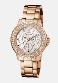 Die rose-goldene Metalluhr verfügt über ein rundes Zifferblatt mit einem weißen Ziffernblatt, drei Unterzifferblättern und einer mit Kristallen verzierten Lünette. Das Armband hat ein glattes Gliederdesign.