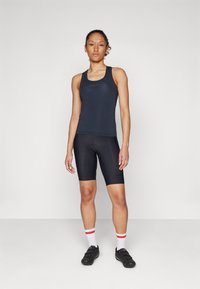 Marineblå tanktopp og svarte sykkelshorts sett. Tanktoppen har en slank passform og subtil logo; shortsene har en sømløs finish og midtbens lengde.