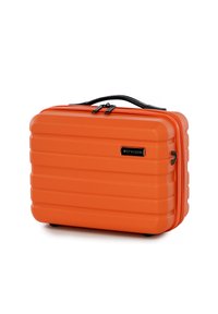 Orange hard-shell suitcase with a ribbed design, featuring a black handle and zipper. Compact, durable material and four black feet on the base.