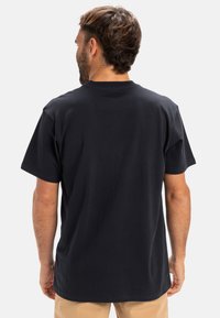 Black cotton t-shirt with short sleeves and a crew neck. Features a relaxed fit and smooth texture. Back view shows simplicity in design.