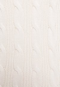 Tissu tricoté blanc avec un motif épais de point torsadé créant des textures tressées verticales.