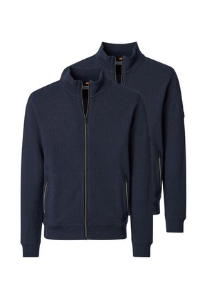 Twee marineblauwe jasjes met volledige ritssluiting, opstaande kragen en ritszakken aan de zijkant, afgebeeld tegen een witte achtergrond.