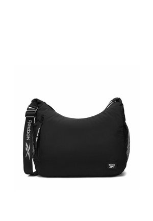 Czarna torba na ramię Reebok z regulowanym paskiem, przednią kieszenią na suwak oraz siateczkową kieszenią z boku, z logo Reebok na przedniej części i pasku.