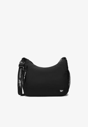Černá ramenní taška Reebok s nastavitelným popruhem, přední kapsou na zip a síťovanou boční kapsou, s logem Reebok na přední straně a na popruhu.