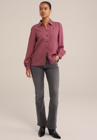 Camicia a bottoni di colore prugna chiaro con strisce verticali, maniche lunghe e dettagli ai polsini, abbinata a jeans dritti grigi e stivaletti neri con tacco.