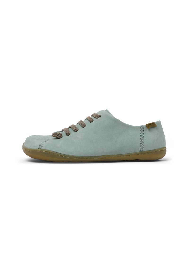 Scarpa in suede verde chiaro con punta arrotondata, lacci marroni e suola in gomma flessibile. Cuciture accentuate lungo i lati.