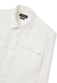Camicia button-up bianca in lino con colletto classico, due tasche frontali e bottoni in perla. Tessuto liscio con poche pieghe.