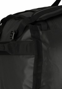 Borsa a sacca nera realizzata in materiale impermeabile, con spallacci regolabili, parte superiore piatta e tasca laterale con chiusura a fibbia. Texture liscia.