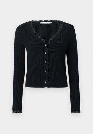 Juodas raukšlėtas kardiganas su ilgomis rankovėmis, turintis V formos iškirptę ir nėrinių apdailą palei iškirptę bei rankogalius. Priekyje su šešių mygtukų užsegimu.