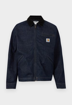 Chaqueta vaquera azul oscuro con cremallera, cuello negro, dos bolsillos laterales, un bolsillo en el pecho con cremallera y un pequeño parche con el logo de Carhartt en el pecho.