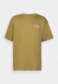 Camiseta de algodón verde oliva con mangas cortas, escote redondo y logo blanco "Carhartt Work In Progress 1989" impreso en el pecho.