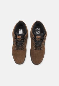 Brown suede lace-up shoes feature a round toe, black textile lining, and contrasting black laces. Includes a branded leather tag on the tongue.