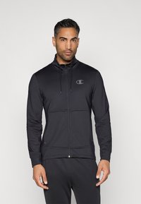 Schwarze zip-up Sportjacke mit hohem Kragen, Kordelzug und einem Logo auf der Brust. Hergestellt aus glattem, dehnbarem Stoff.